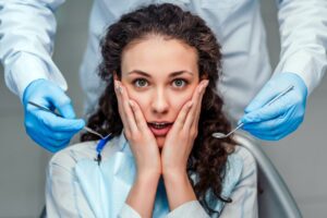Dental patient holding face with both hands in fear.